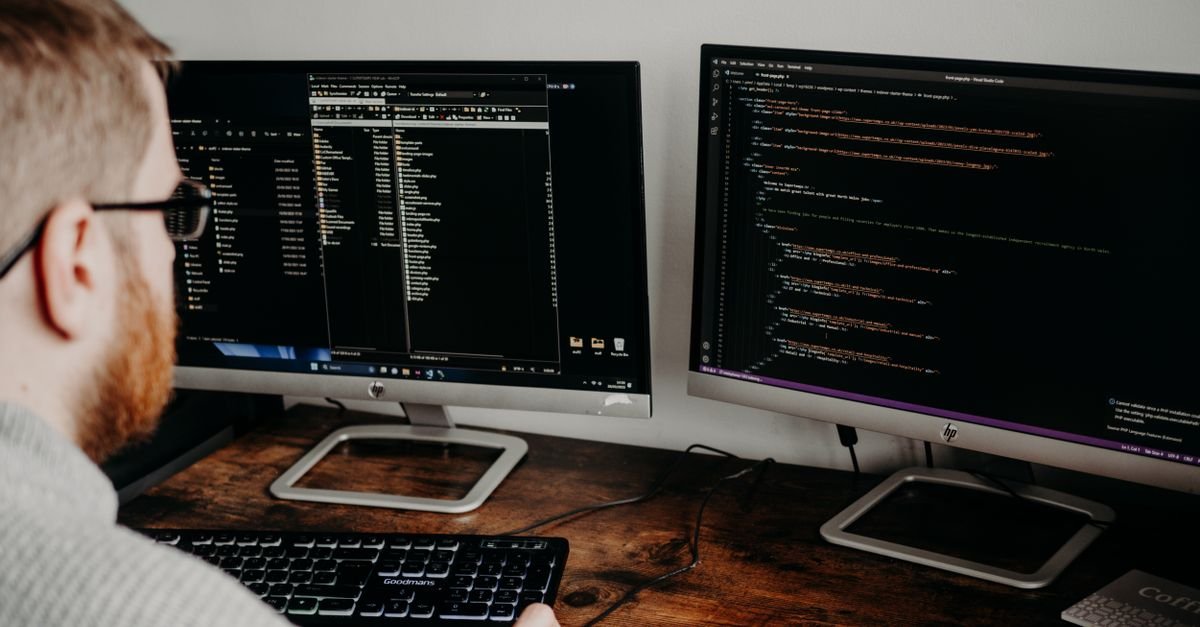 A web designer working on a website layout across two monitors