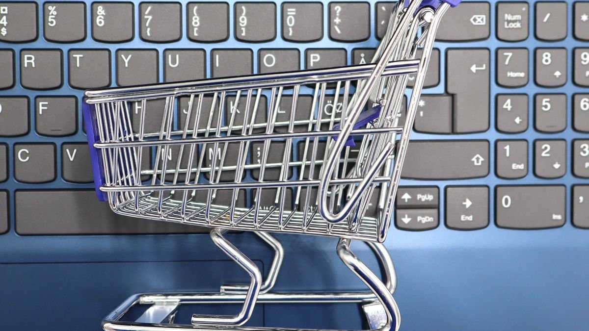 A miniature shopping cart placed on a laptop keyboard, representing online shopping and e-commerce