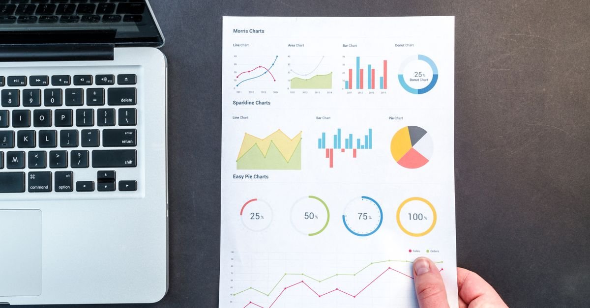 Printed charts and bar graphs laid beside a laptop, representing website analytics and search data
