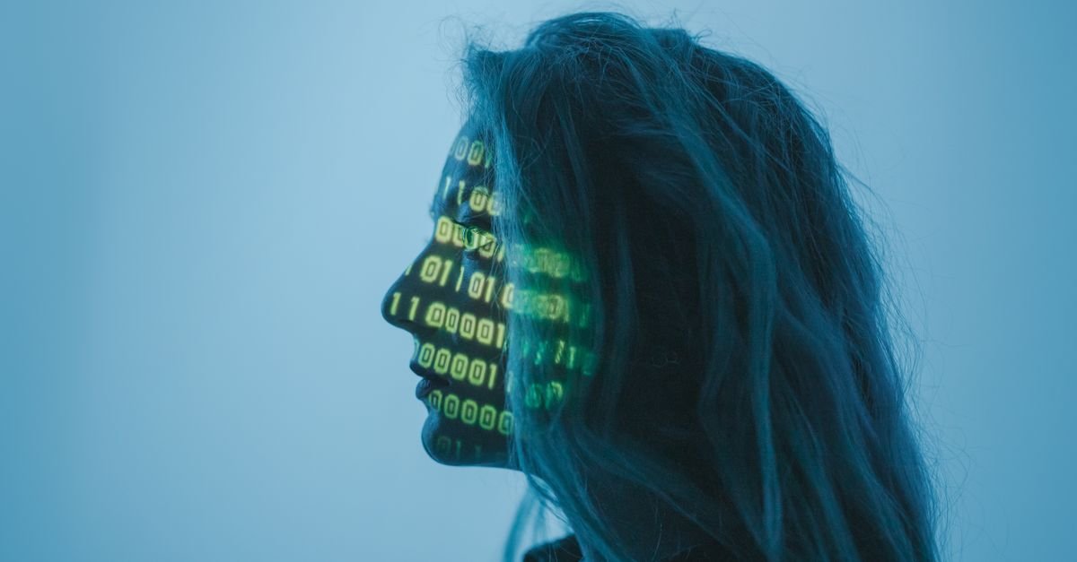 A person's face lit by projected lines of binary code, representing AI in business